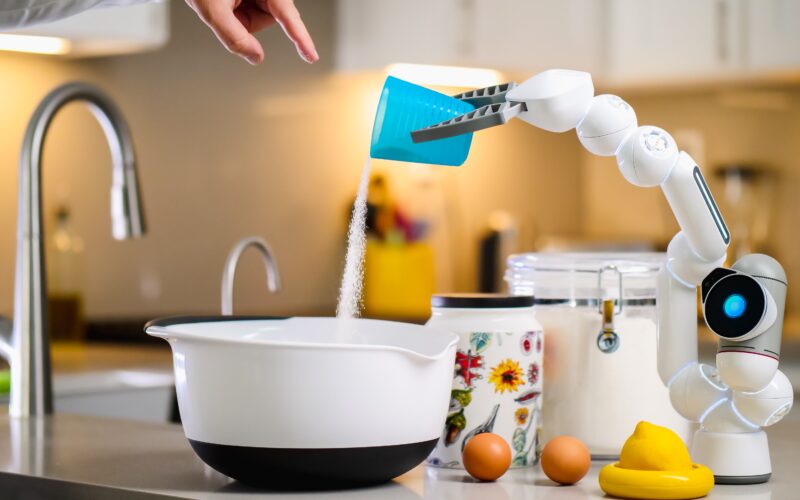 AI revolutionizing food manufacturing: A robotic arm pouring granulated sugar into a bowl.